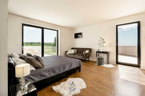 A bedroom with a bed, a sofa, a TV, and a balcony. - Vibrant modern 5-BR Villa for 10+2, with pool and a sea view (Višnjan)