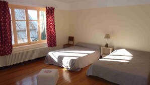 A room with two beds, a small table, a chair, and a radiator. - Rental apartment type 2 in mountain house in Risoul - 05600 (Risoul)