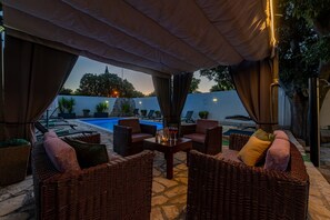 Ein Sitzbereich im Freien mit Korbmöbeln und einem Tisch mit Blick auf einen Swimmingpool.