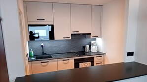 Een moderne keuken met een zwart aanrecht, roestvrijstalen apparatuur en lichtgekleurde kasten.