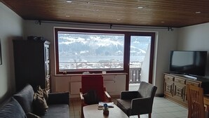 Een woonkamer met een groot raam, een bank, een salontafel en een televisie.