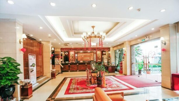 Un vestíbulo amplio con alfombra roja, un candelabro y un mostrador de recepción.