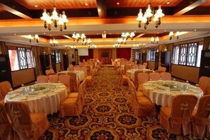 A banquet hall with round tables, chairs, and a carpeted floor. - Yazhi Hotel Kaiping (Kaiping)