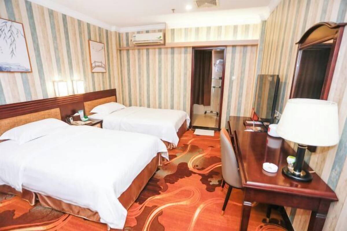 Een hotelkamer met twee bedden, een bureau, een stoel, een spiegel en een kledingkast.