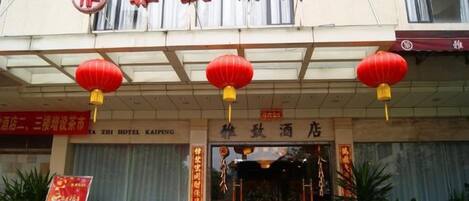 A hotel entrance with a traditional Chinese architectural style, featuring a red lantern decoration above the entrance.