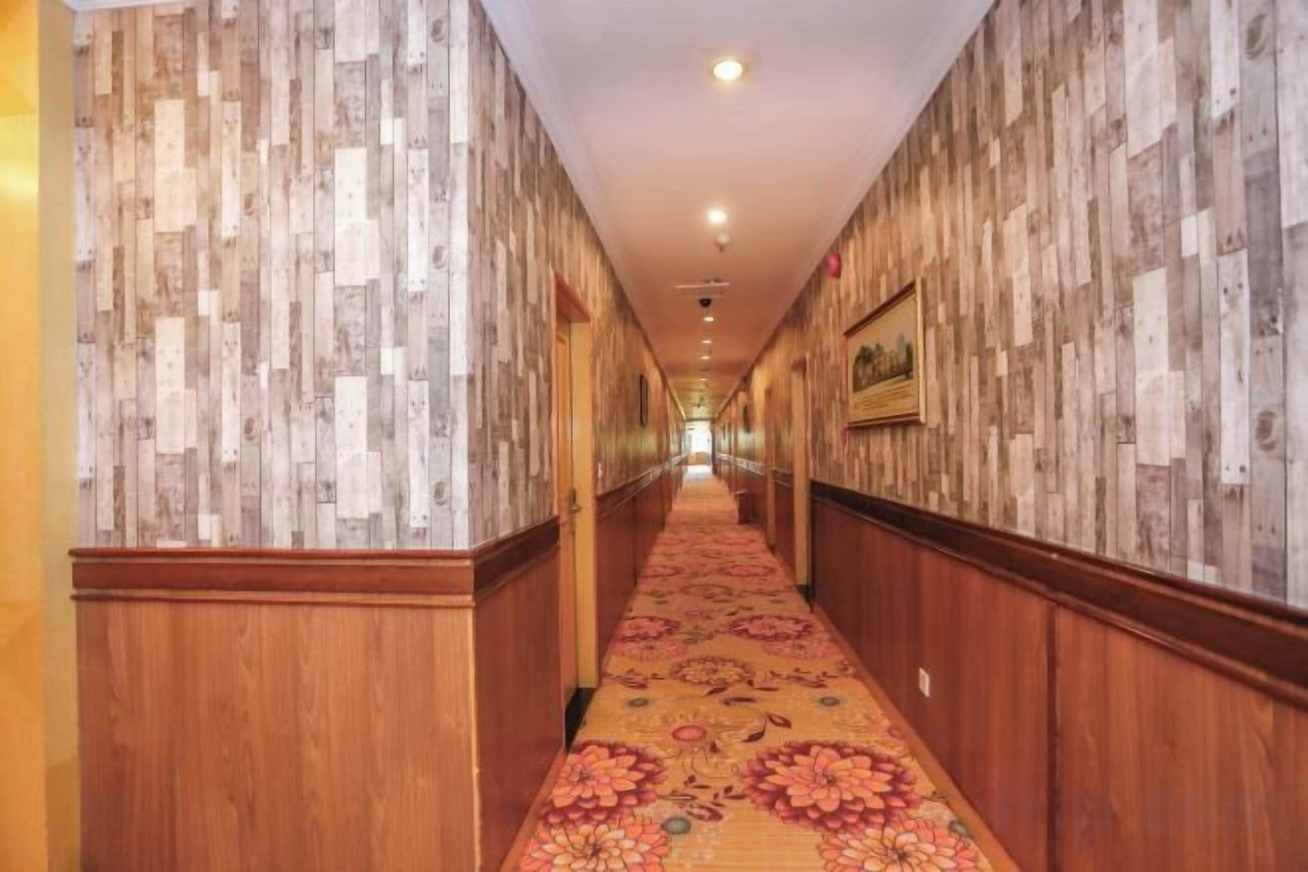 A hotel corridor with wooden paneling on the walls and a patterned carpet.