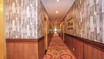 A hotel corridor with wooden paneling on the walls and a patterned carpet.