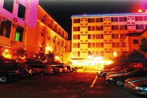 A multi-story hotel with a parking lot in front.