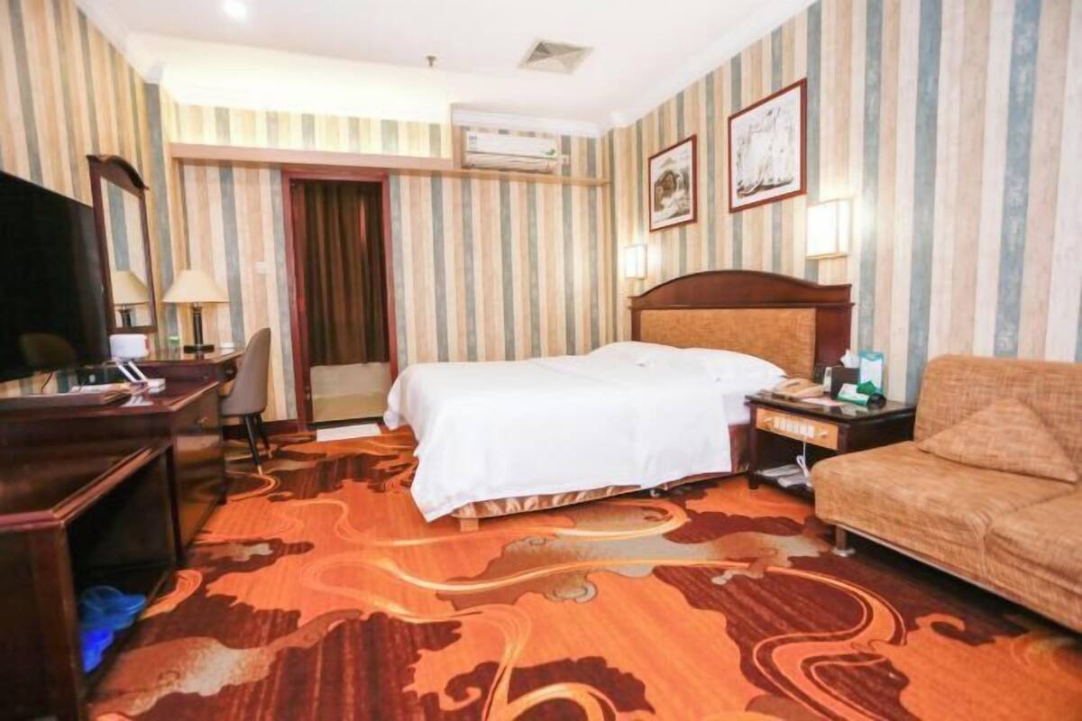 Een hotelkamer met een bed, een bureau, een stoel, een bank en een televisie.