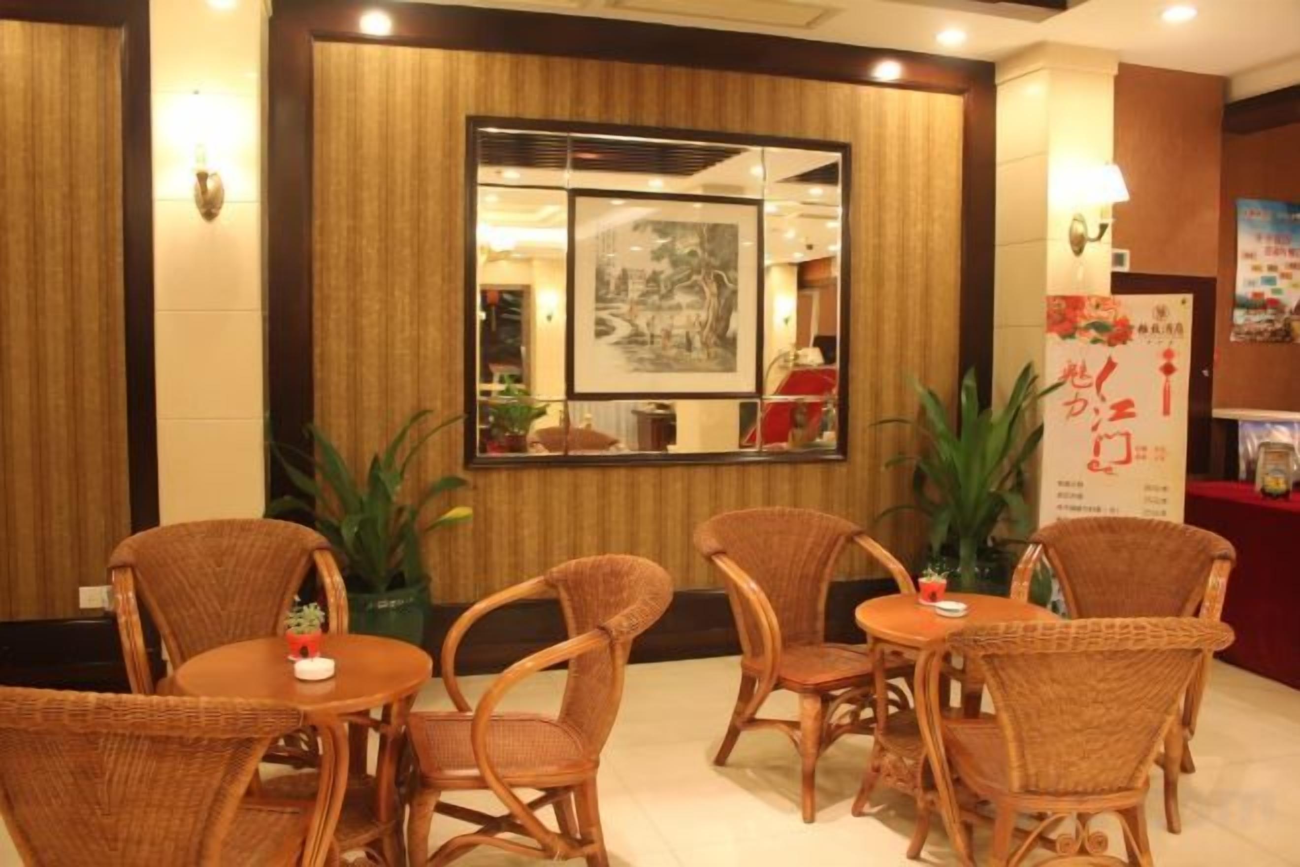 Un interior de restaurante con sillas y mesas de mimbre, una pared de madera con un espejo, y un cartel en la pared.