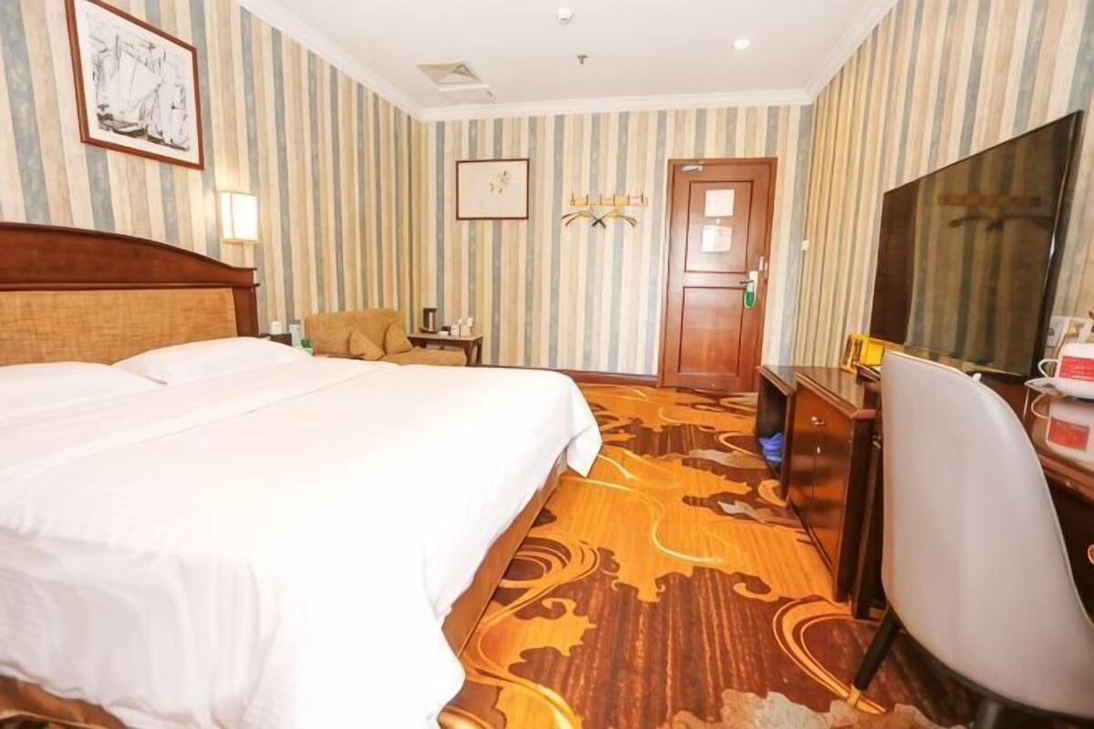 Een hotelkamer met een groot bed, een bureau, een stoel, een televisie en een deur.
