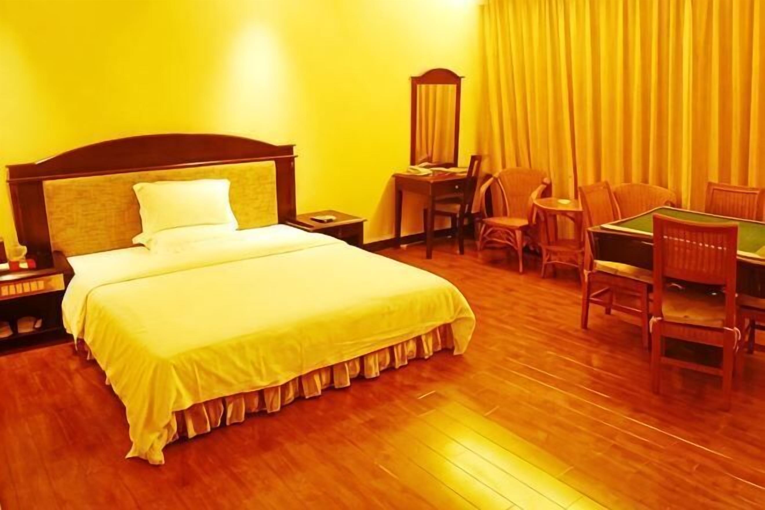 Una habitación de hotel con cama, escritorio, sillas y espejo.