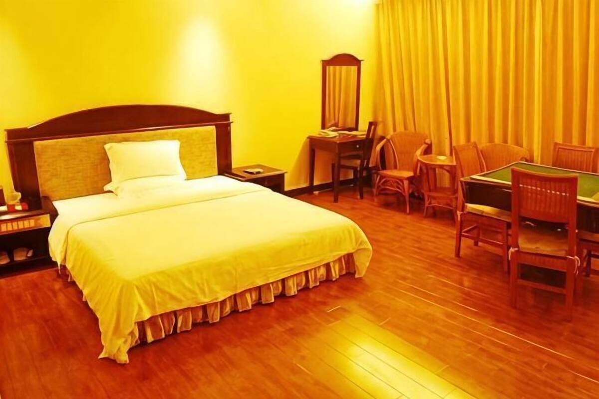 Een hotelkamer met een bed, een bureau, stoelen en een spiegel.