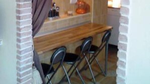 Una cocina con mostrador de madera, dos sillas y un arco de ladrillo.