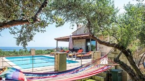 Ein Poolbereich mit Hängematte, Sitzgelegenheiten im Freien und Blick aufs Meer.