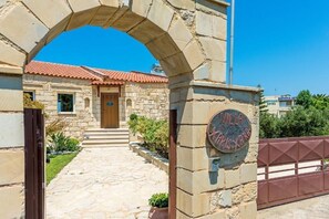 A stone building with a red-tiled roof, a wooden door, and a sign reading "Villa".