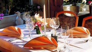 A table set for dining with a candle, glasses, and a vase of flowers. - Hotel Restaurant Fasanerie (Marburg)