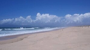 Ein Strand mit klarem Himmel und Wellen.