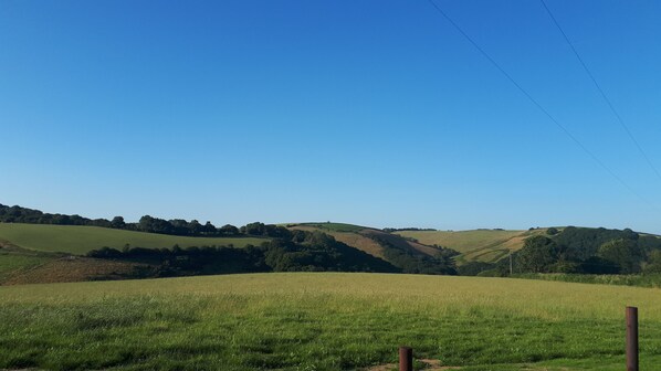 A rural landscape with rolling hills, a clear blue sky, and a fence in the foreground. - Recently renovated Traditional Country Cottage (Looe)