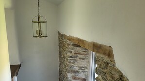 En trappa med en dekorativ vägg av sten, en hängande lampa och en vit bänk.