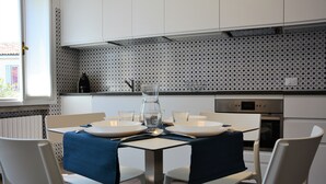A modern kitchen with white cabinets, a patterned backsplash, and a dining area with a table set for two. - historic dwelling (Mira)