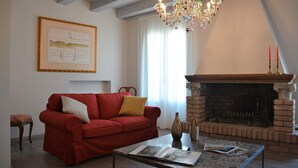 A living room with a red sofa, a fireplace, a chandelier, and a framed document on the wall. - historic dwelling (Mira)