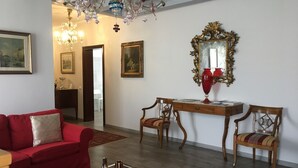 A living room with a red sofa, a wooden table, two chairs, a chandelier, and a mirror with an ornate frame. - historic dwelling (Mira)