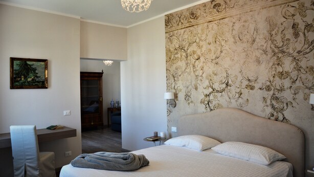A hotel room with a bed, a desk, a chair, a lamp, and a painting on the wall. - historic dwelling (Mira)