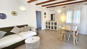 Een woonkamer met een bank, een eettafel met stoelen, een kast en decoratieve borden aan de muur.