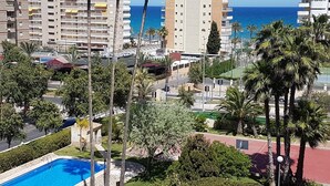 A high-rise building with multiple balconies overlooking a clear blue sea.