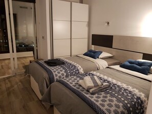 Un dormitorio con dos camas, una puerta corrediza de vidrio y un armario.