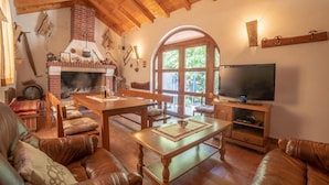 Una sala de estar acogedora con chimenea, sofás de cuero, una mesa de comedor de madera y un televisor.