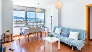 Una sala de estar moderna con un ventanal grande, un sofá, una mesa de comedor con sillas y un televisor.