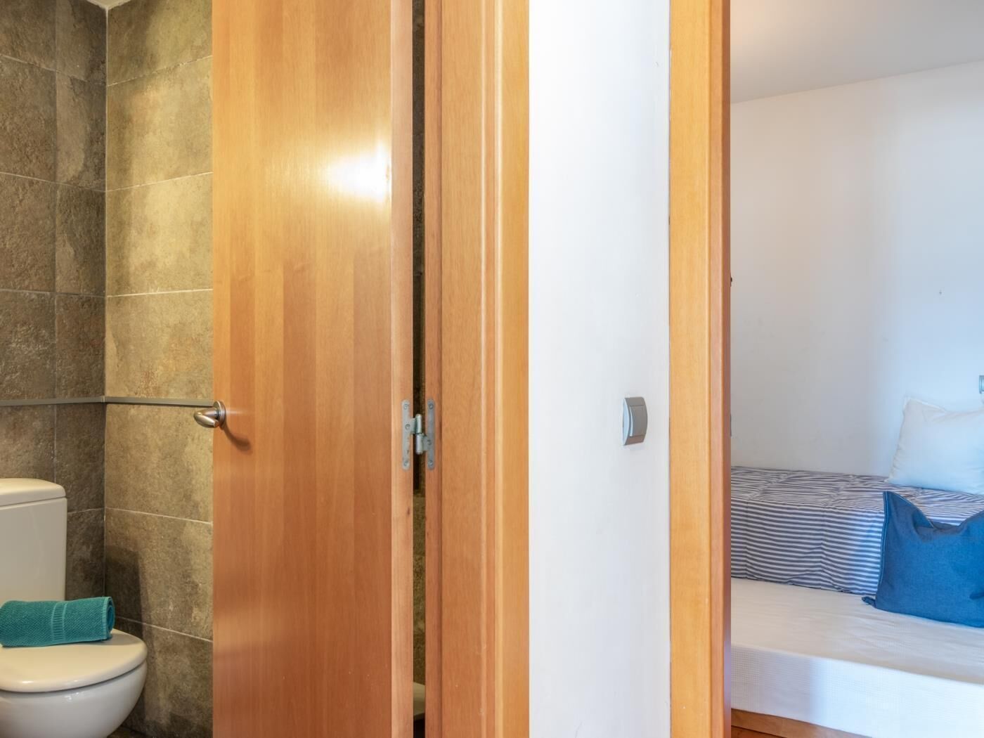 Un bagno con il water e la doccia, e una camera da letto con un letto e cuscini.