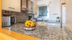 Una cocina moderna con encimeras de granito, electrodomésticos de acero inoxidable y un amplio ventanal.