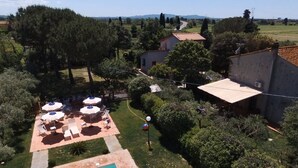 Ein Wohnhaus mit Swimmingpool, Sitzbereich im Freien mit Sonnenschirmen und einem umzäunten Garten.