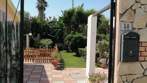 Un vialetto lastricato con un muro in pietra, una cassetta postale e un recinto in legno che conduce a un giardino.