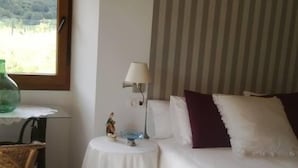Une chambre à coucher avec un lit, une table de chevet avec une lampe, une chaise et une vue sur l’extérieur par une fenêtre.