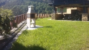 Un bâtiment rustique, doté de fondations en pierre et d’un toit en tuiles, entouré d’une pelouse et d’une clôture en bois.
