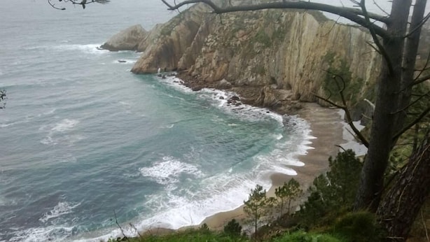 Un paysage côtier caractérisé par des falaises rocheuses et une plage de sable.