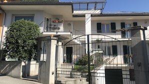 Un edificio de dos pisos con un balcón, una entrada con portón y vistas a la montaña.