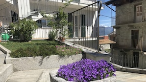 Un patio con macetas de piedra con flores moradas, una escalera y una vista de montañas al fondo.