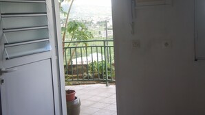 Quarto com porta que dá para uma varanda e vista de uma paisagem distante.