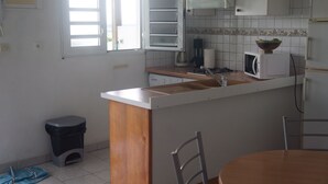Uma cozinha compacta com bancada de madeira, pia, micro-ondas e janela com persianas.