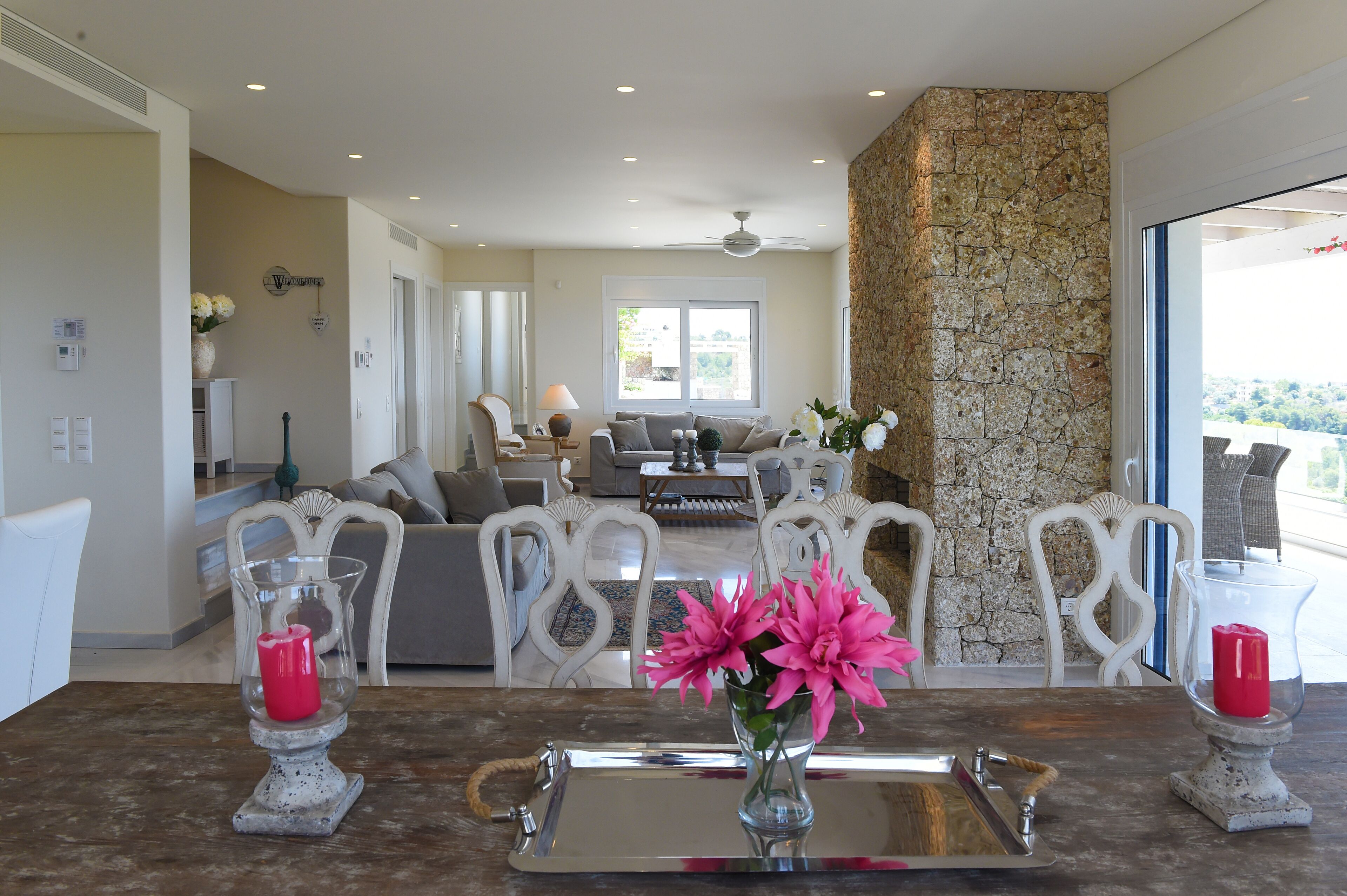 A spacious living area with a stone accent wall, a dining table with candles, and a view of the outdoors.