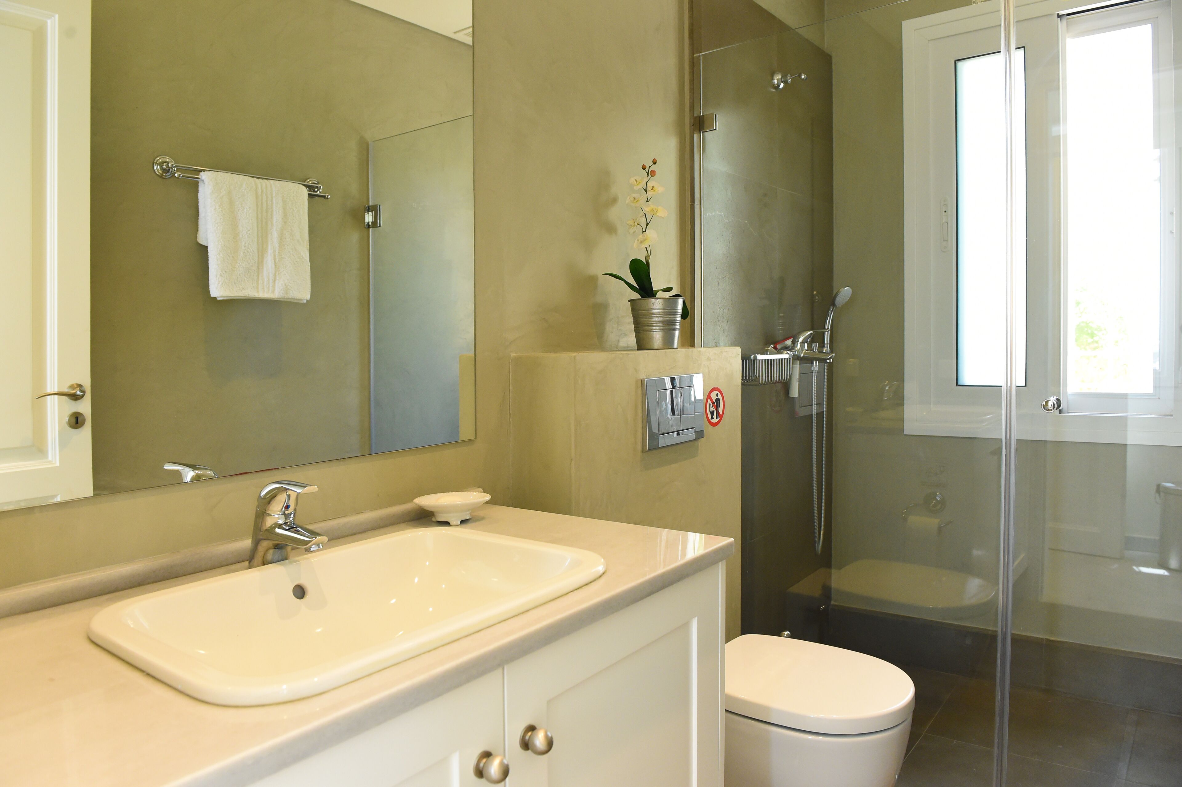 Une salle de bain moderne équipée d’un lavabo, de toilettes et d’une douche à parois de verre.