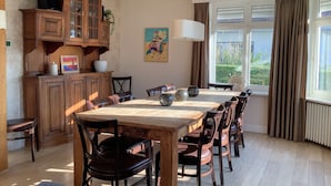 Un coin repas avec une table et des chaises en bois, un meuble avec des portes en verre et une fenêtre avec des rideaux.