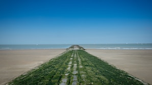 Un long sentier étroit qui mène à une formation rocheuse sur une plage.