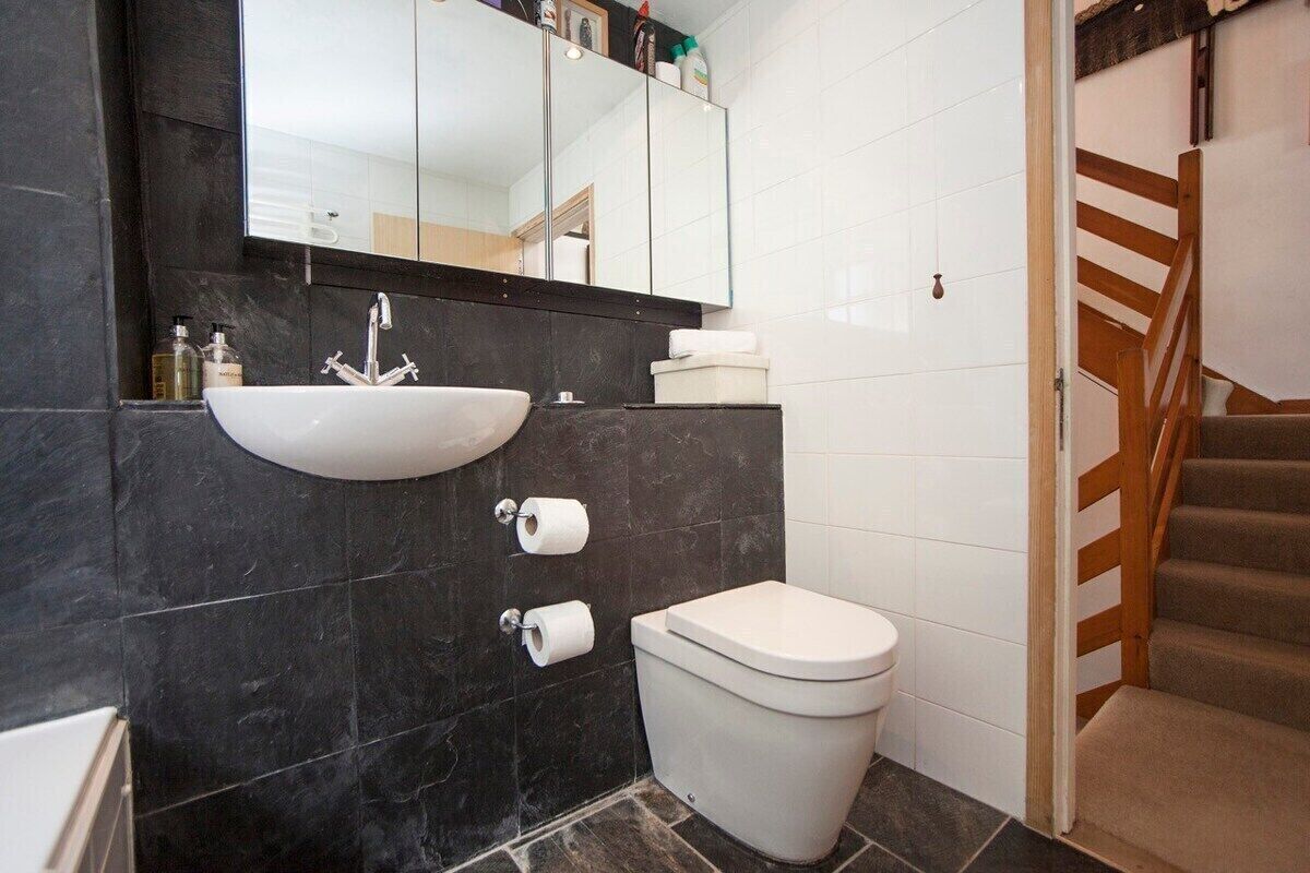 Un bagno con lavandino bianco, servizi igienici e uno specchio sopra il lavandino.