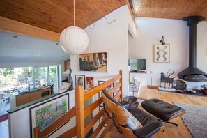 Een moderne woonkamer met een houten plafond, een open haard en een eethoek met uitzicht.